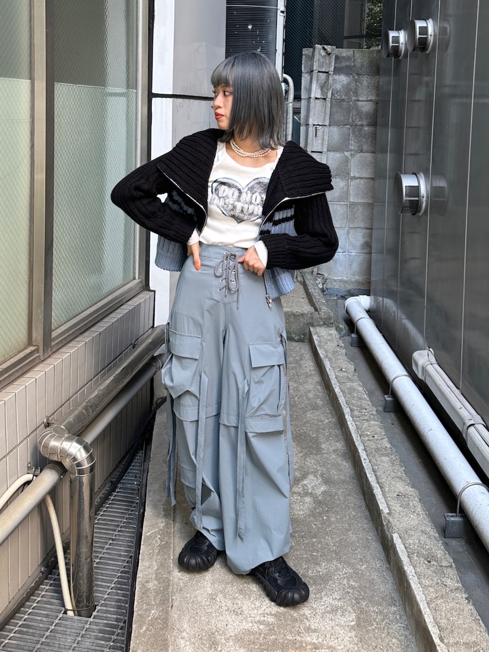 グレー系のその他パンツ、ホワイト系のTシャツ/カットソー、ブラック系のニット/セーターを着用したレディースの秋コーディネートの2枚目の写真