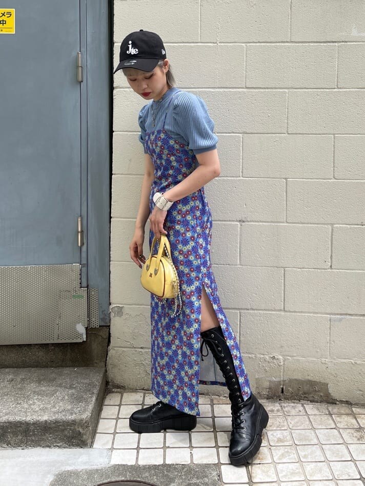 ブラック系のブーツ、ブルー系のニット/セーター、イエロー系のボストンバッグを着用したレディースの夏コーディネートの2枚目の写真