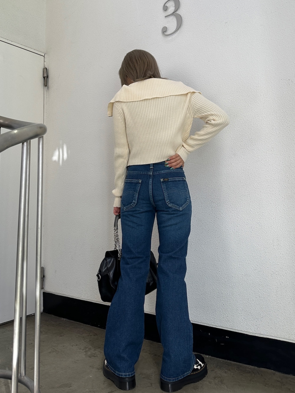 ブルー系のデニムパンツ、ホワイト系のカーディガン/ボレロ、ブラック系のTシャツ/カットソーを着用したレディースの冬コーディネートの2枚目の写真