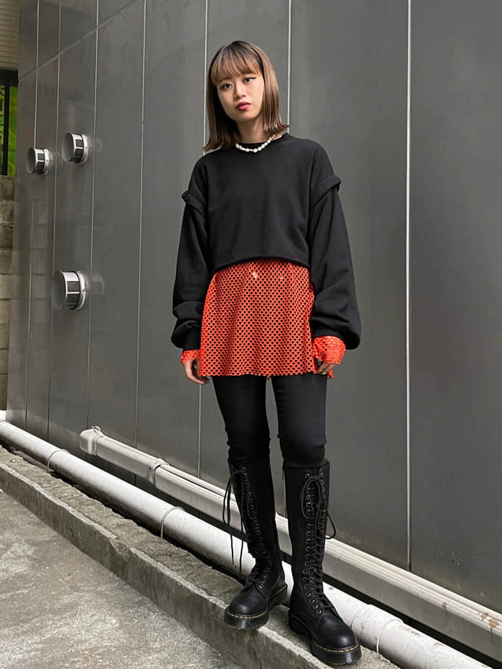 ブラック系のブーツ、ブラック系のTシャツ/カットソー、オレンジ系のTシャツ/カットソーを着用したレディースの冬コーディネートの2枚目の写真