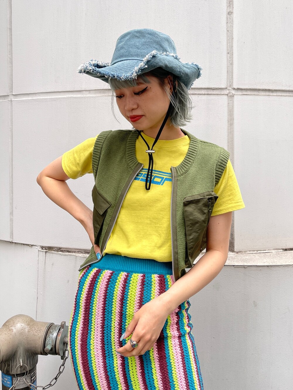 イエロー系のTシャツ/カットソー、グリーン系のベスト、ブルー系のスカートを着用したレディースの春コーディネートの8枚目の写真