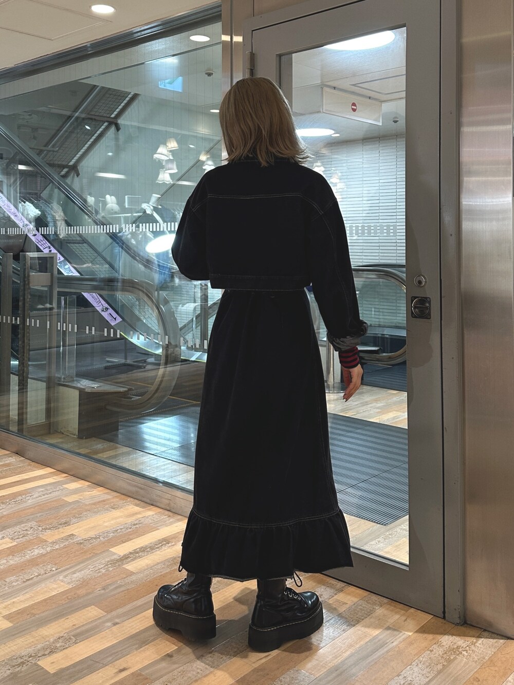 レッド系のTシャツ/カットソー、ブラック系のワンピース、ブラック系のブーツを着用したレディースの夏コーディネートの3枚目の写真