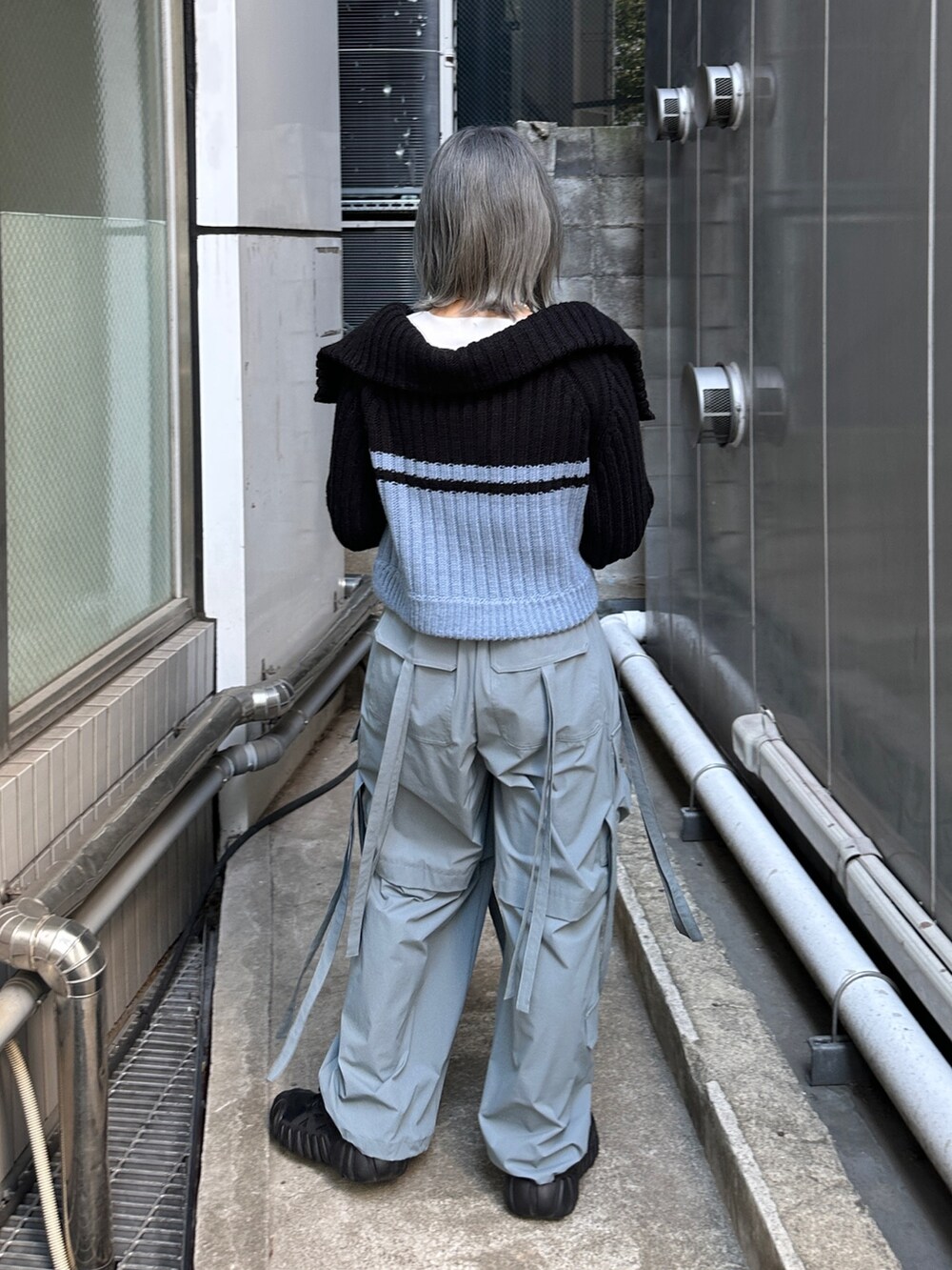 グレー系のその他パンツ、ホワイト系のTシャツ/カットソー、ブラック系のニット/セーターを着用したレディースの秋コーディネートの4枚目の写真