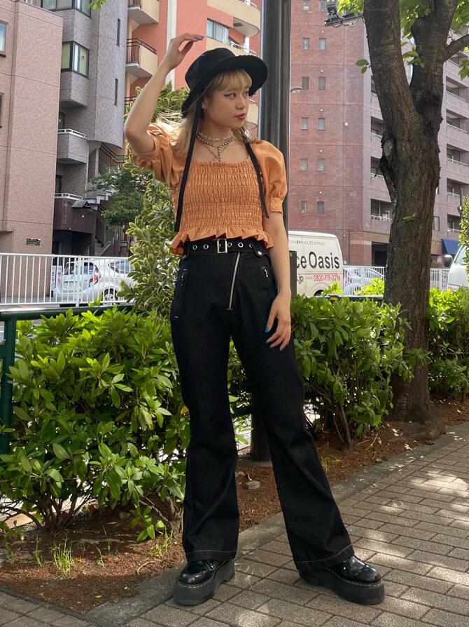 オレンジ系のシャツ/ブラウス、ブラック系のデニムパンツ、ブラック系のハットを着用したレディースの春コーディネートの3枚目の写真