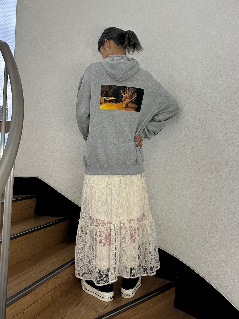 グレー系のパーカー、ホワイト系のスカート、ブラック系のスニーカーを着用したレディースの秋コーディネートの3枚目の写真