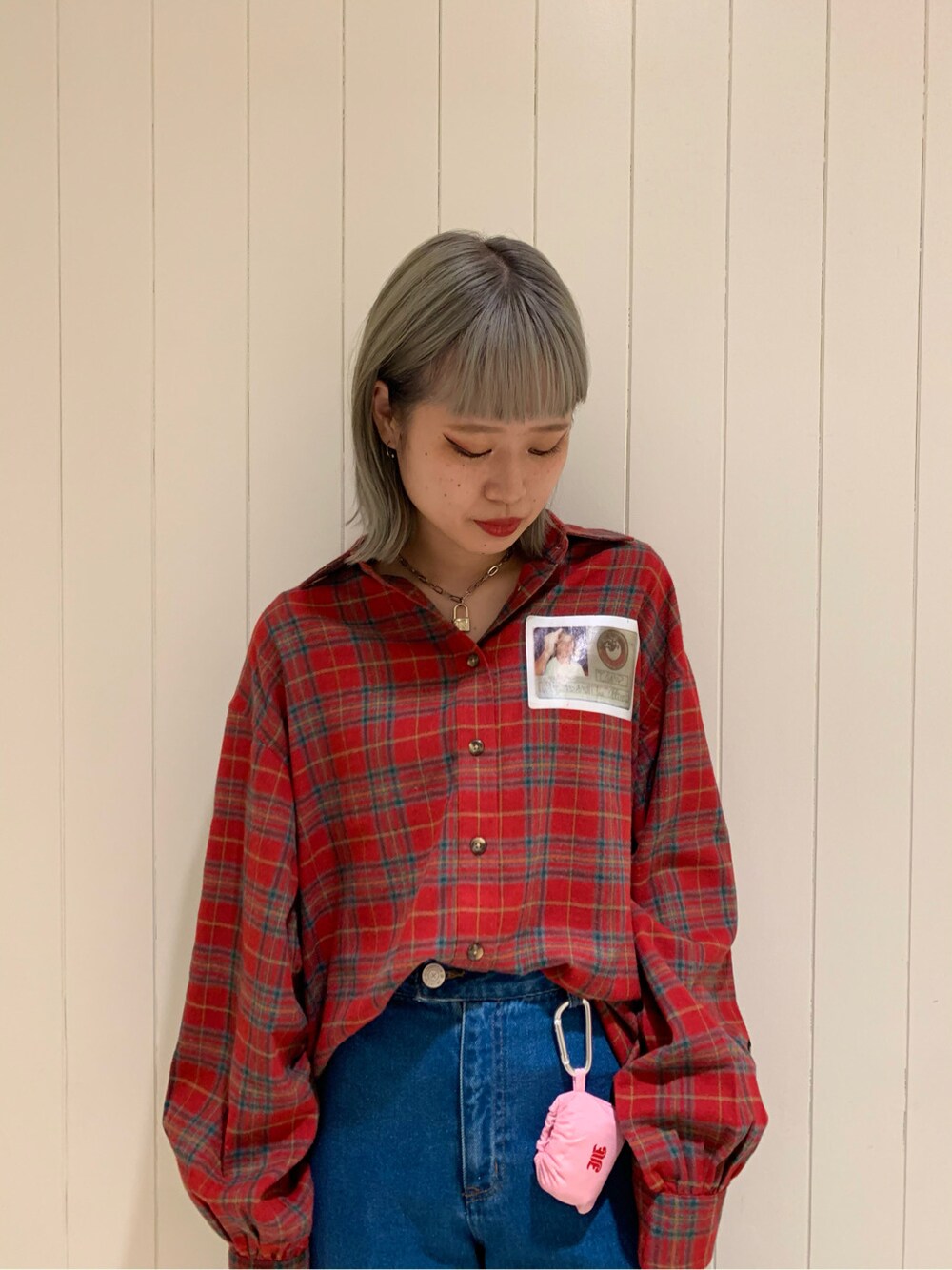 レッド系のシャツ/ブラウス、ピンク系のエコバッグ/サブバッグ、ブルー系のデニムパンツを着用したレディースの秋コーディネートの2枚目の写真