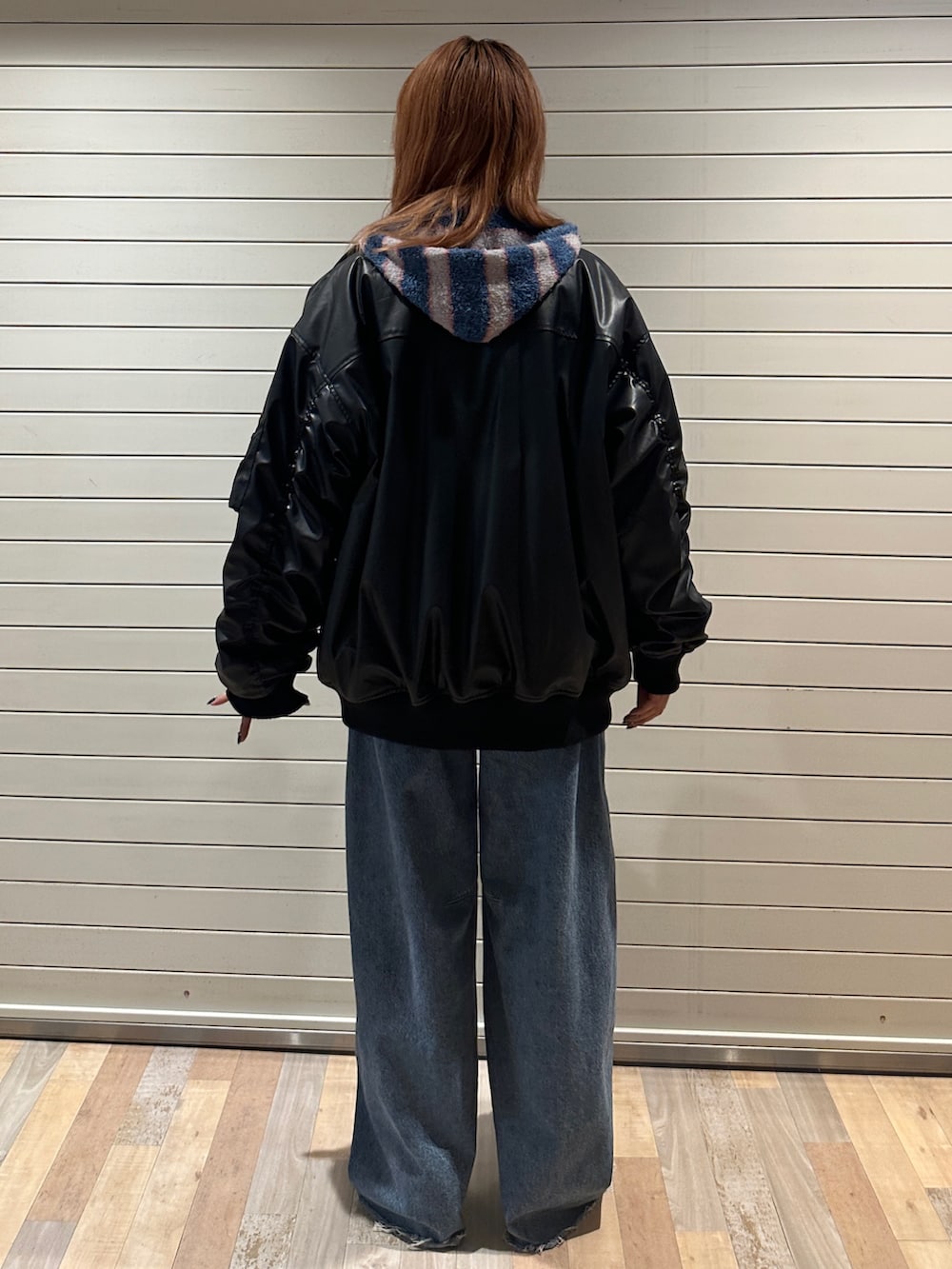 ブラック系のブルゾン、ブルー系のパーカー、ブルー系のデニムパンツを着用したレディースの秋コーディネートの3枚目の写真