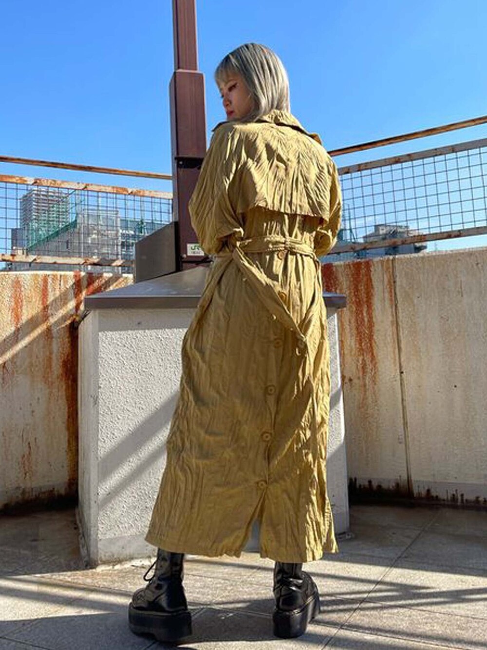 ベージュ系のトレンチコート、ブルー系のワンピースを着用したレディースの冬コーディネートの3枚目の写真