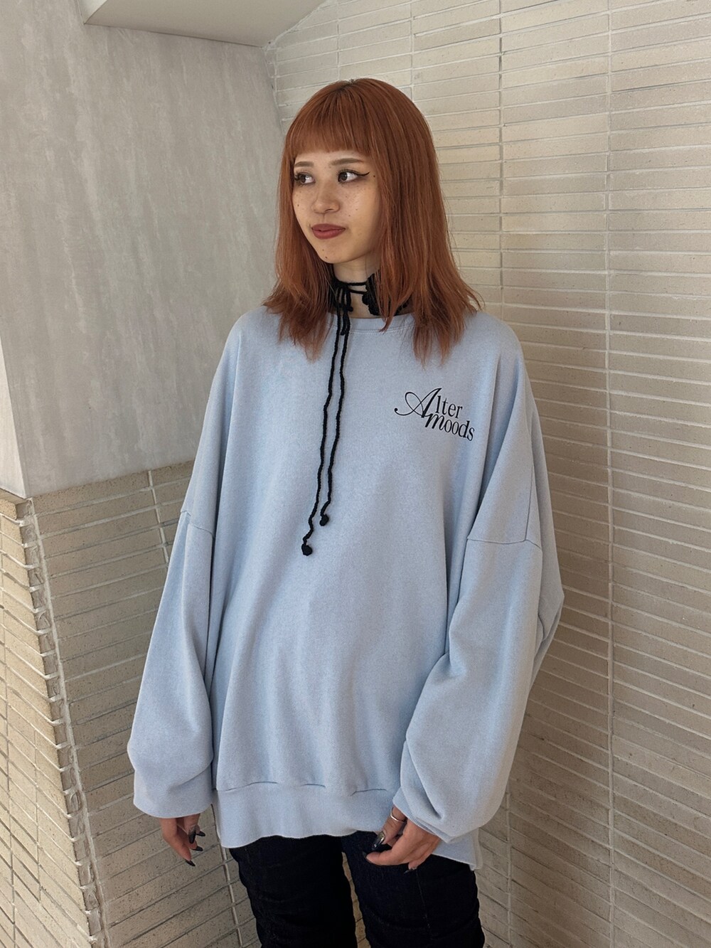 ブルー系のスウェット、ブラック系のパンプス、ブルー系のデニムパンツを着用したレディースの秋コーディネートの5枚目の写真