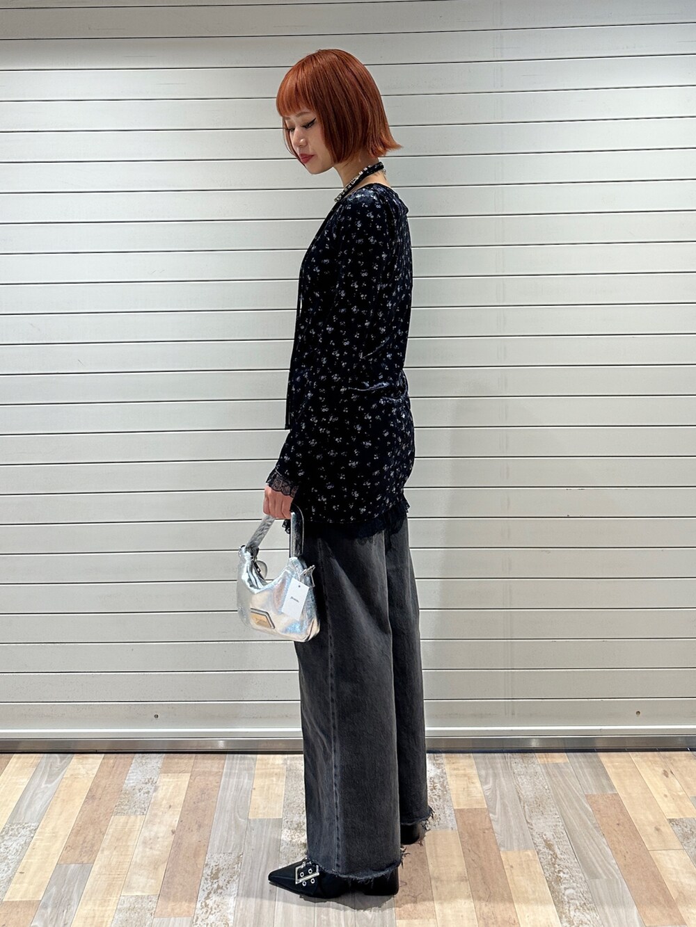 ブルー系のワンピース、シルバー系のハンドバッグ、ブラック系のデニムパンツを着用したレディースの冬コーディネートの3枚目の写真