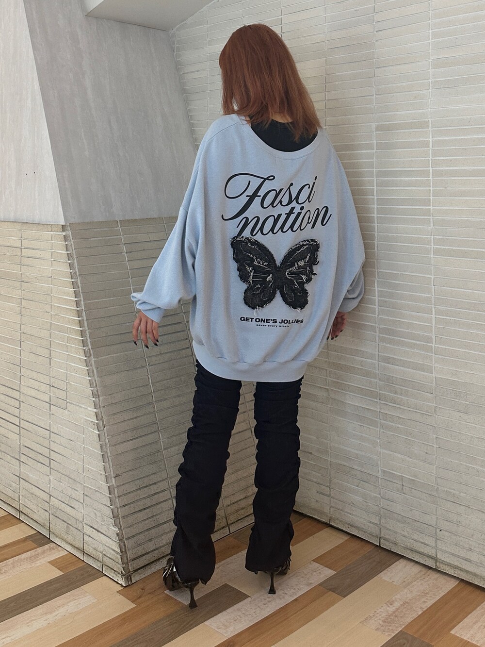 ブルー系のスウェット、ブラック系のパンプス、ブルー系のデニムパンツを着用したレディースの秋コーディネートの3枚目の写真