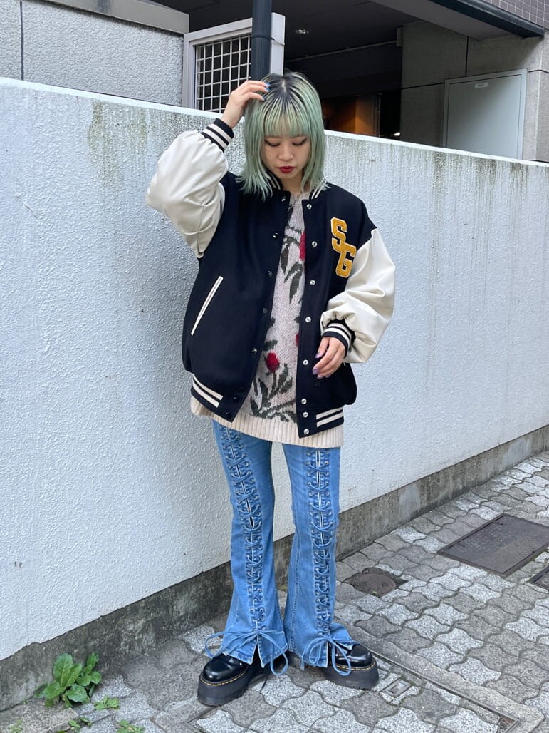 ブラック系のスタジャン、ホワイト系のニット/セーター、ブルー系のデニムパンツを着用したレディースの秋コーディネートの4枚目の写真