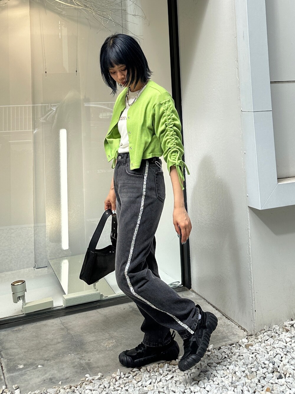 グリーン系のTシャツ/カットソー、ブラック系のデニムパンツ、ブラック系のハンドバッグを着用したレディースの夏コーディネートの3枚目の写真