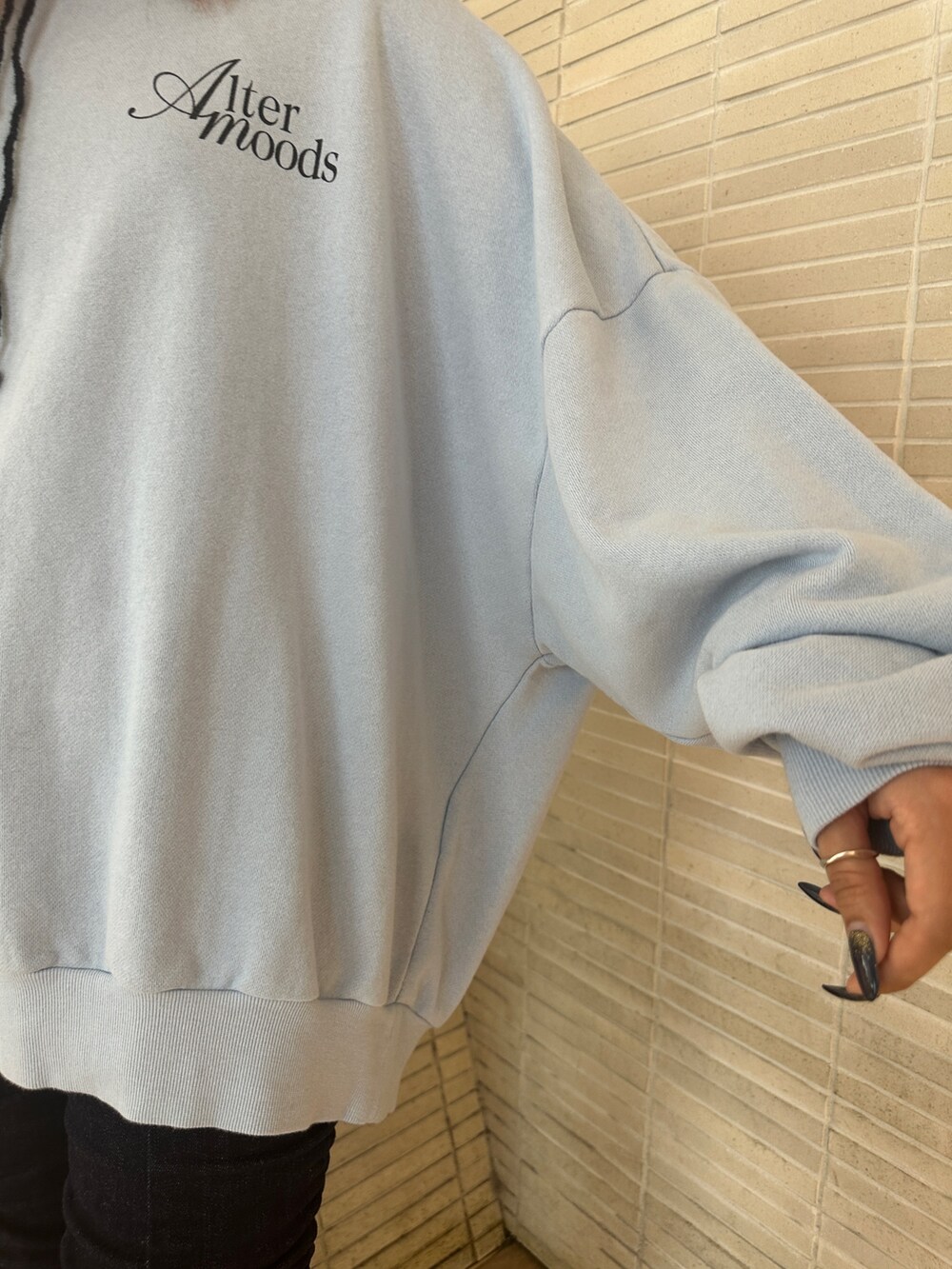 ブルー系のスウェット、ブラック系のパンプス、ブルー系のデニムパンツを着用したレディースの秋コーディネートの7枚目の写真