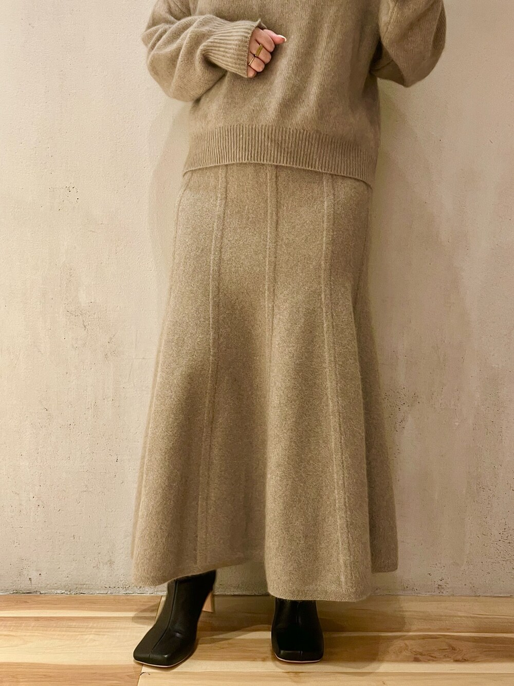 ベージュ系のニット/セーター、ベージュ系のスカート、ブラック系のブーツを着用したレディースの秋コーディネートの6枚目の写真