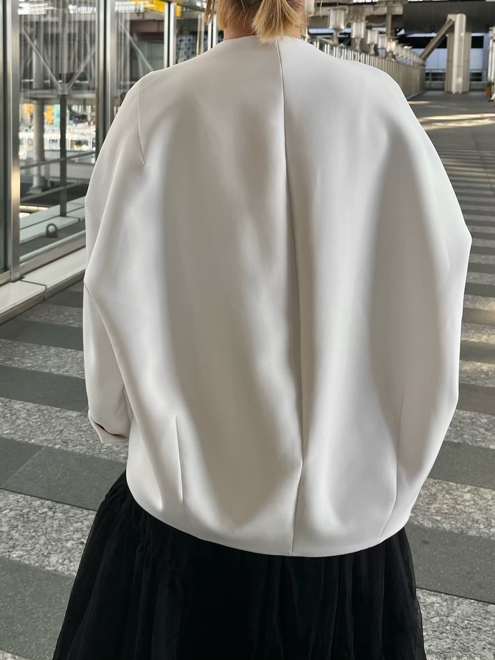 ベージュ系のノーカラーコート、ブラック系のタンクトップ、ブラック系のスカートを着用したレディースの冬コーディネートの8枚目の写真