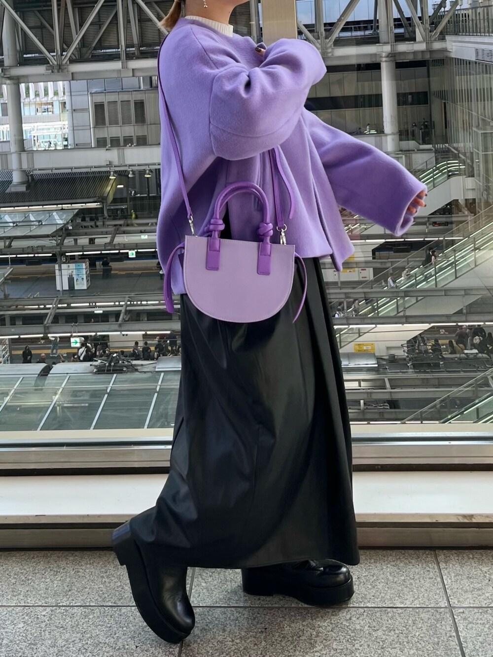 パープル系のノーカラージャケット、ブラック系のジャンパースカート、ホワイト系のニット/セーターを着用したレディースの秋コーディネートの2枚目の写真