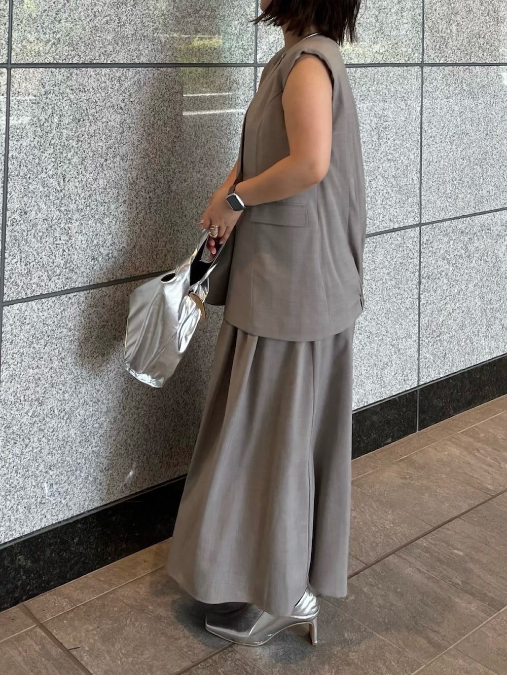 グレー系のワンピース、シルバー系のハンドバッグ、シルバー系のブーツを着用したレディースの夏コーディネートの4枚目の写真