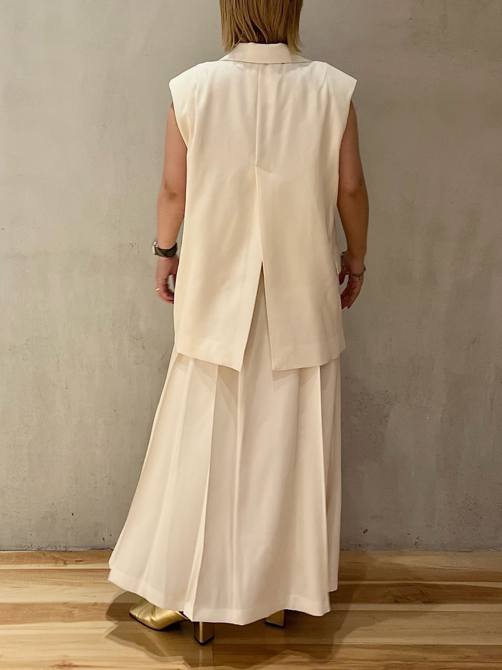 ゴールド系のパンプス、ホワイト系のスカート、ホワイト系のタンクトップを着用したレディースの冬コーディネートの3枚目の写真