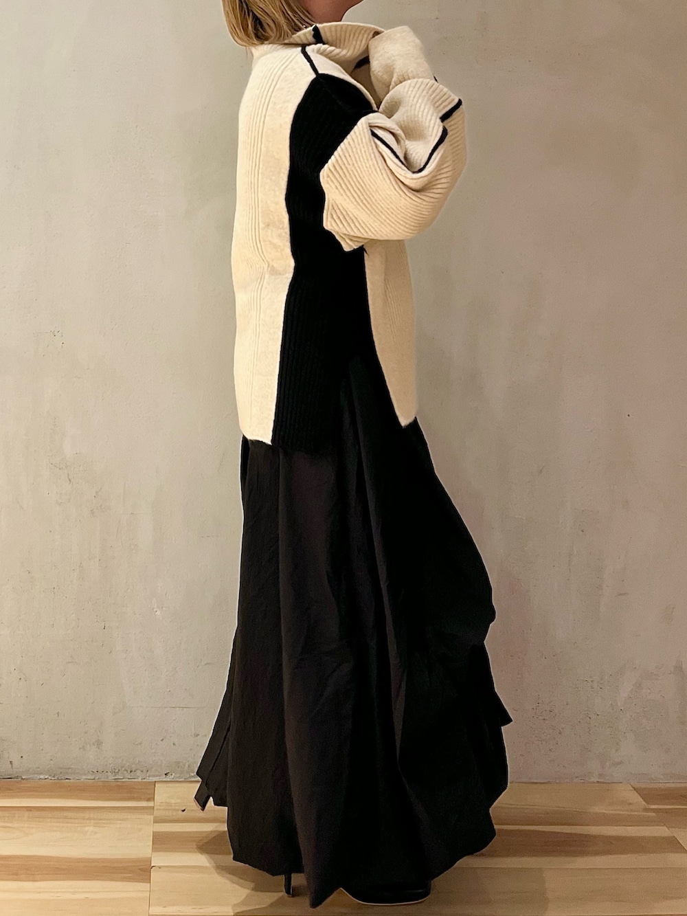 ブラック系のスカート、ホワイト系のニット/セーター、ブラック系のブーツを着用したレディースの秋コーディネートの3枚目の写真