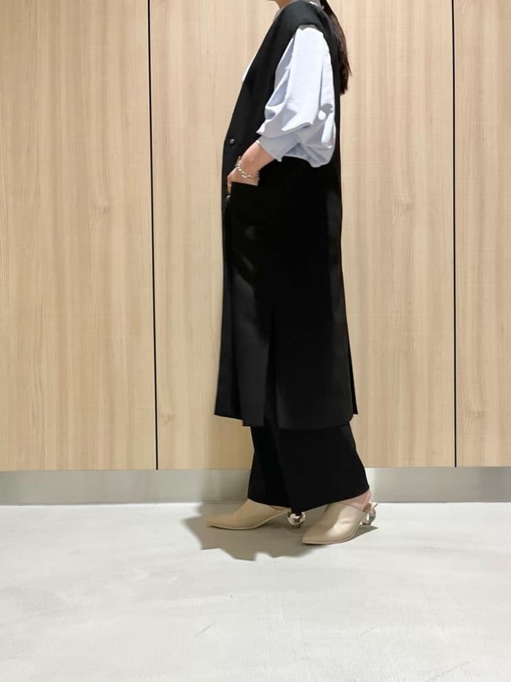 ブラック系のスラックス、ブラック系のノーカラージャケット、ブルー系のシャツ/ブラウスを着用したレディースの春コーディネートの2枚目の写真