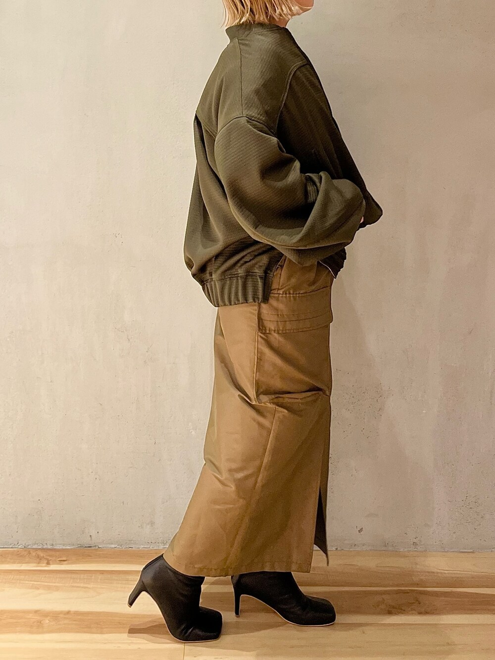 ブラウン系のスカート、ブラック系のブーツ、ブラック系のニット/セーターを着用したレディースの春コーディネートの2枚目の写真