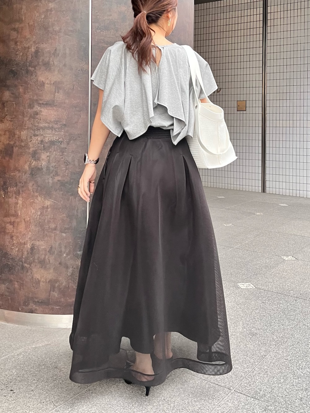 グレー系のTシャツ/カットソー、ブラック系のスカート、ブラック系のパンプスを着用したレディースの春コーディネートの2枚目の写真