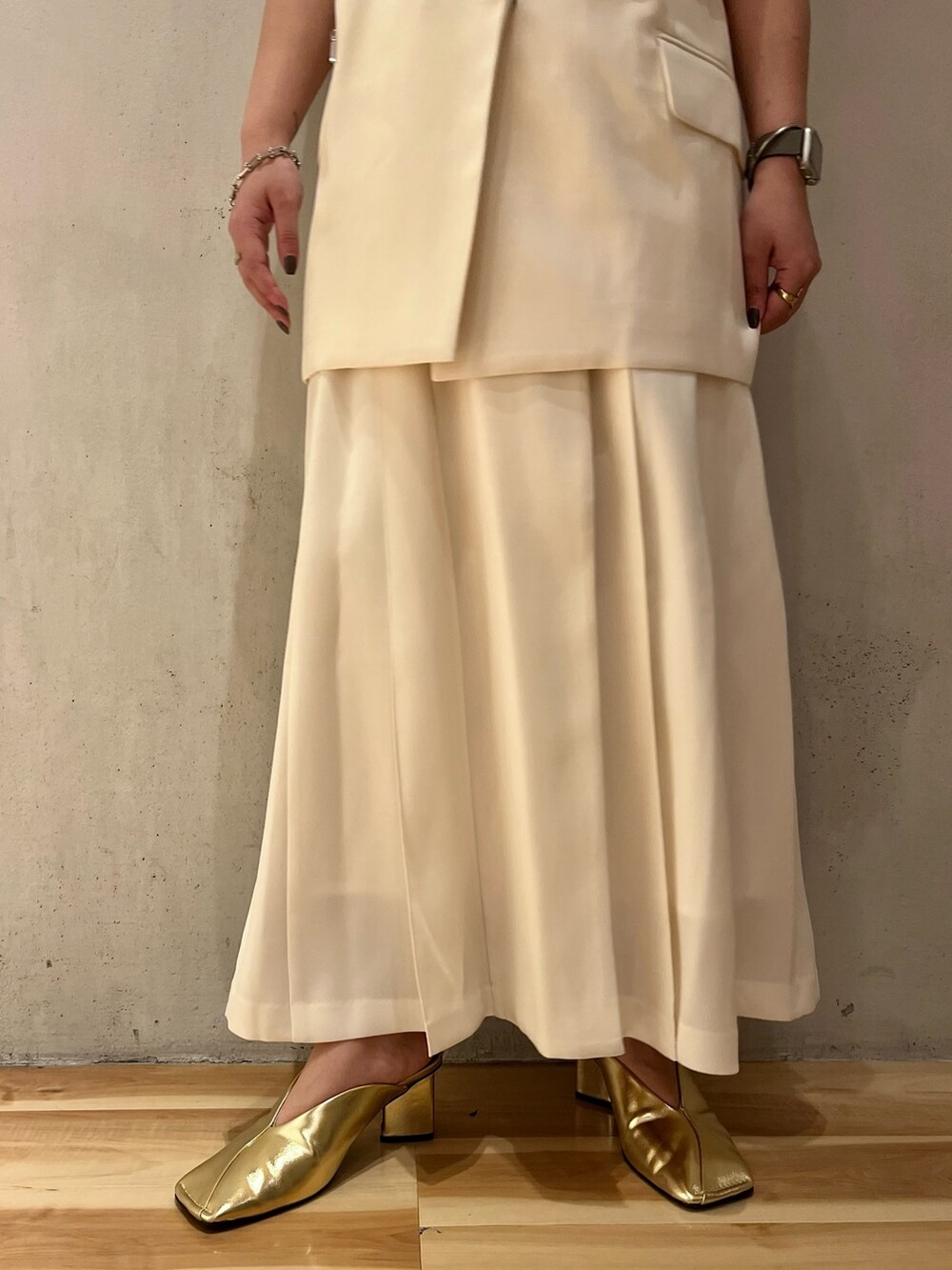 ゴールド系のパンプス、ホワイト系のスカート、ホワイト系のタンクトップを着用したレディースの冬コーディネートの8枚目の写真