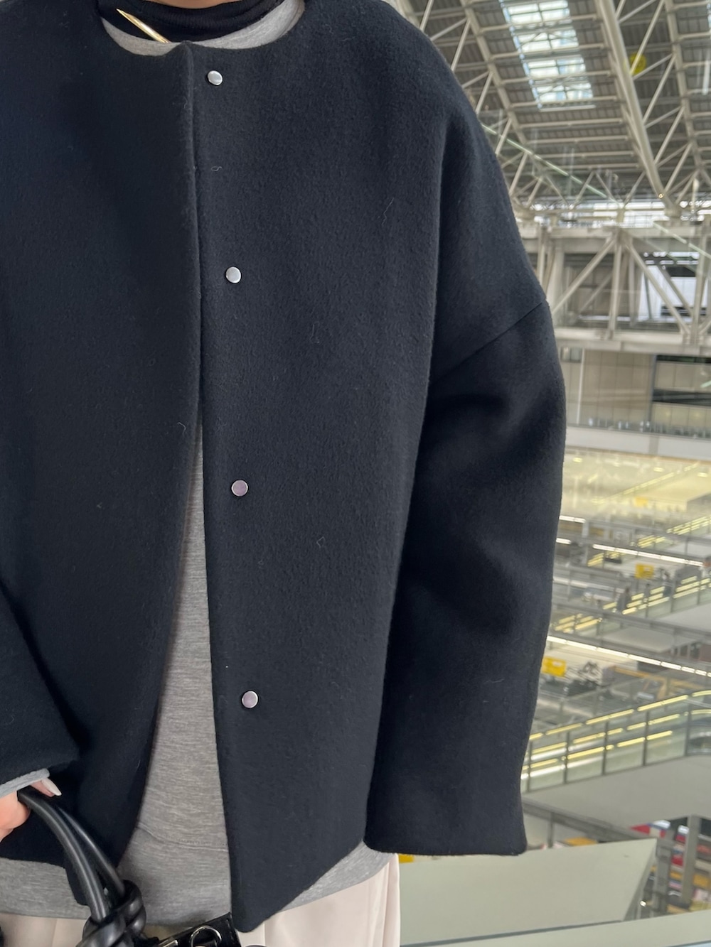 ブラック系のノーカラージャケット、グレー系のワンピース、ブラック系のハンドバッグを着用したレディースの冬コーディネートの7枚目の写真