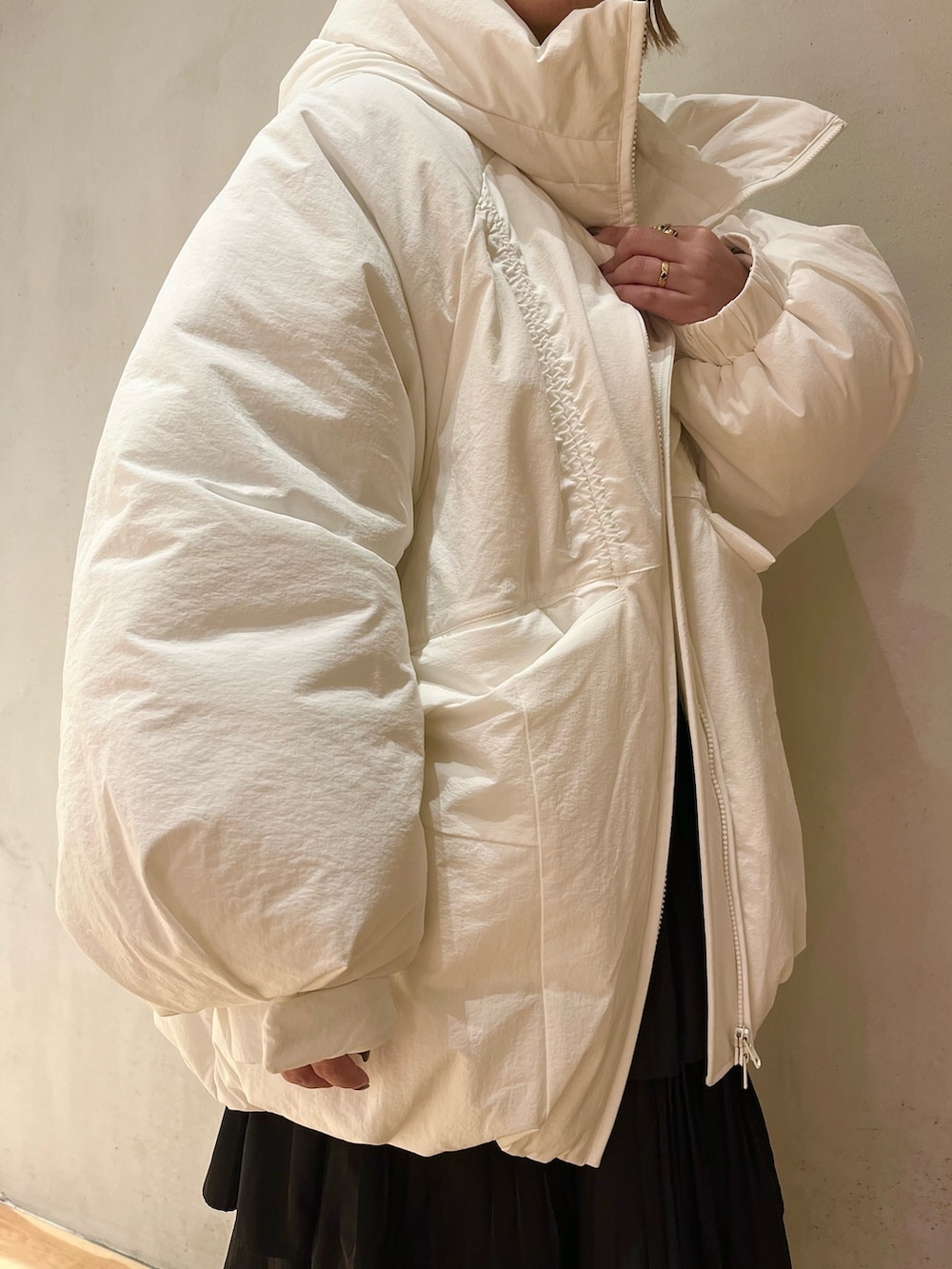 ホワイト系のダウンジャケット/コート、パープル系のニット/セーター、ブラック系のスカートを着用したレディースの夏コーディネートの5枚目の写真