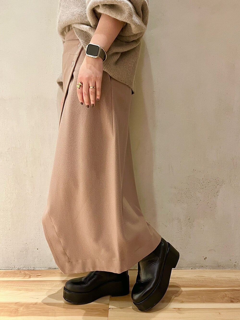 ベージュ系のニット/セーター、ベージュ系のスカート、ブラック系のブーツを着用したレディースの秋コーディネートの8枚目の写真