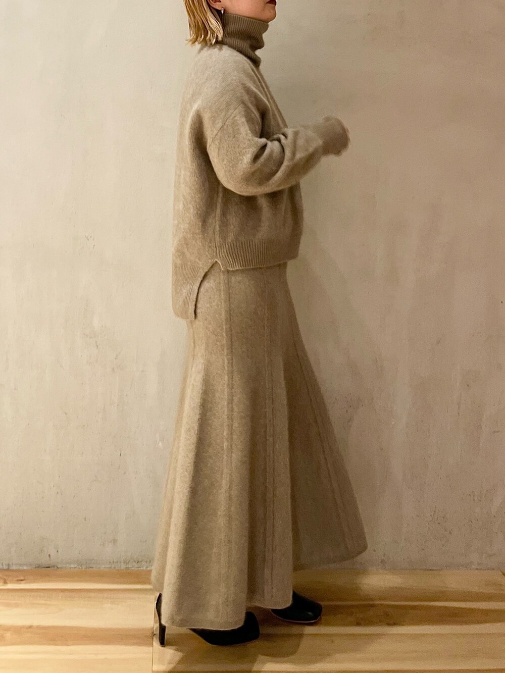 ベージュ系のニット/セーター、ベージュ系のスカート、ブラック系のブーツを着用したレディースの秋コーディネートの4枚目の写真