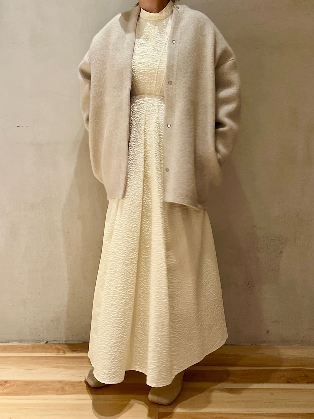 ホワイト系のノーカラージャケット、ホワイト系のワンピース、ベージュ系のブーツを着用したレディースの秋コーディネートの2枚目の写真