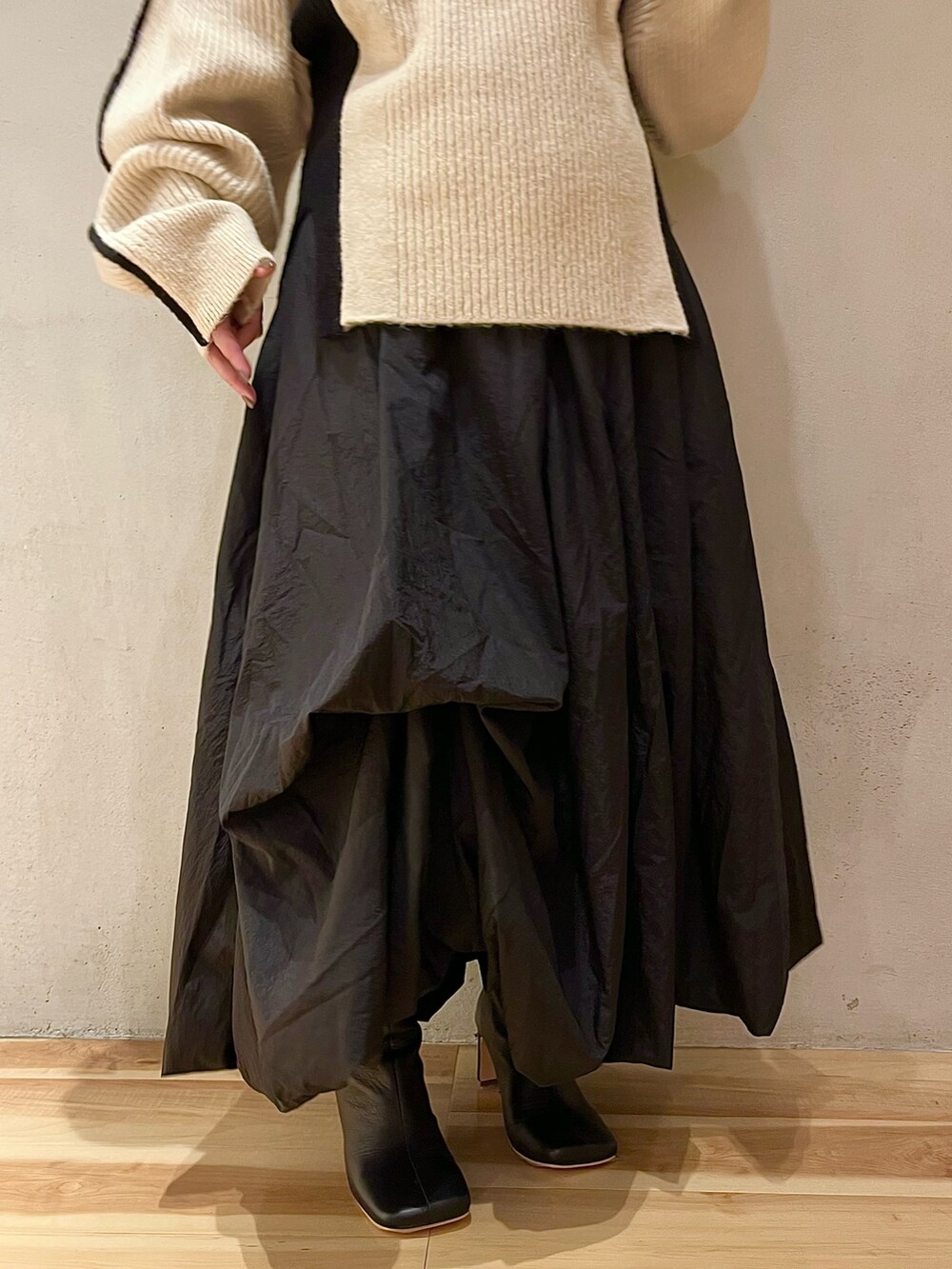 ベージュ系のノーカラーコート、ブラック系のスカート、ブラック系のブーツを着用したレディースの夏コーディネートの8枚目の写真