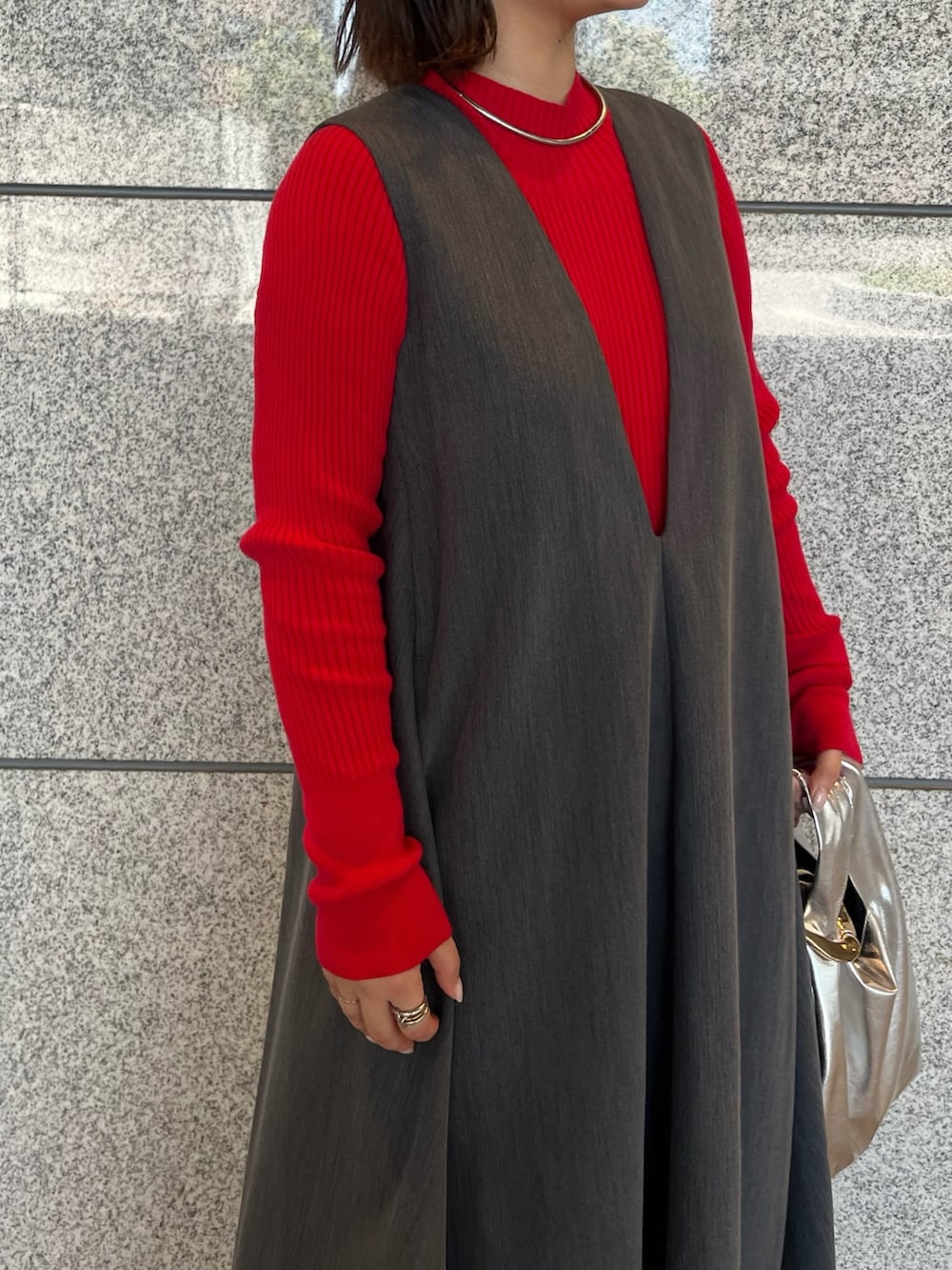 グレー系のジャンパースカート、シルバー系のブーツ、ゴールド系のハンドバッグを着用したレディースの夏コーディネートの6枚目の写真