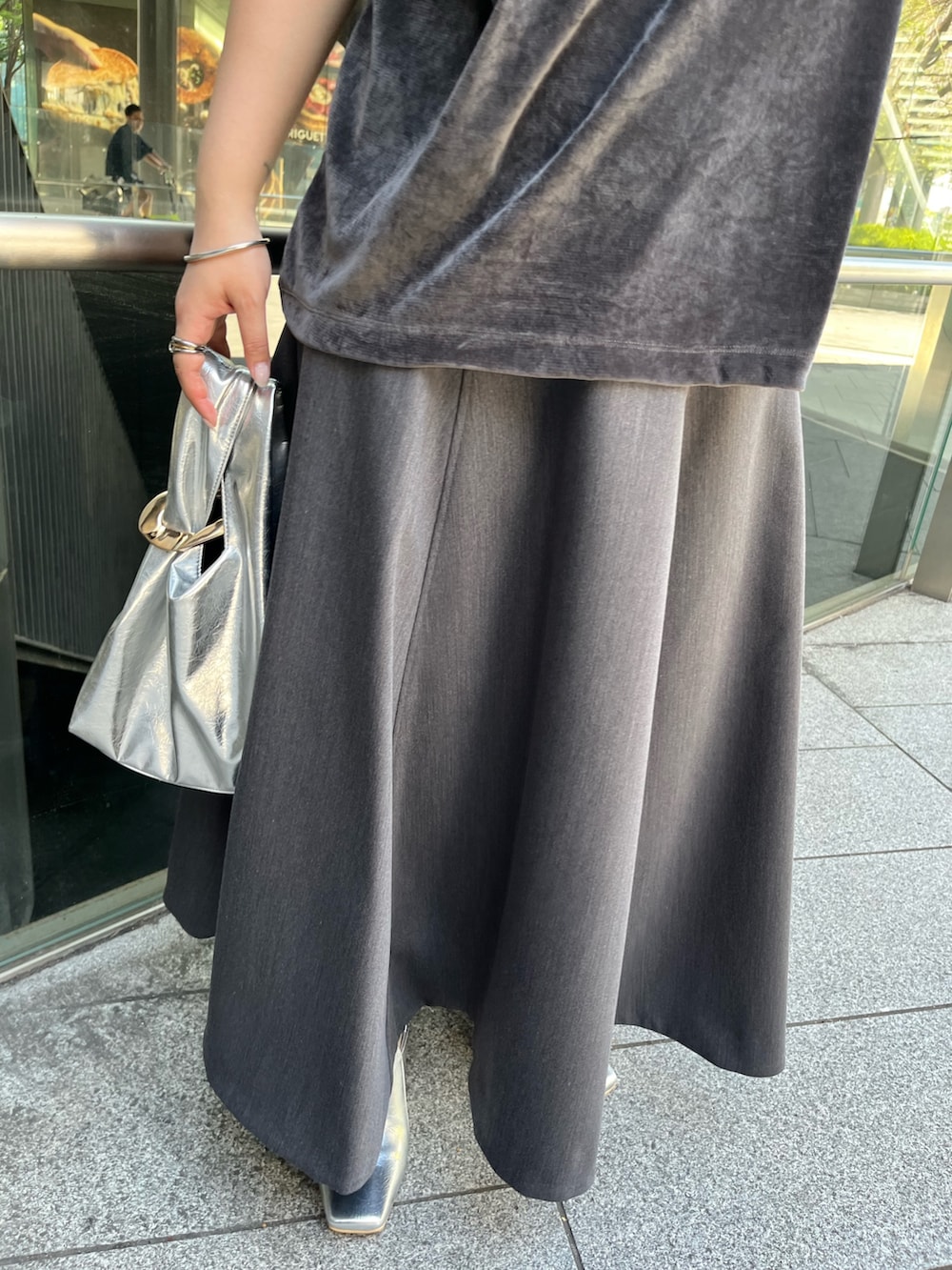 グレー系のスカート、ゴールド系のハンドバッグ、グレー系のTシャツ/カットソーを着用したレディースの夏コーディネートの9枚目の写真