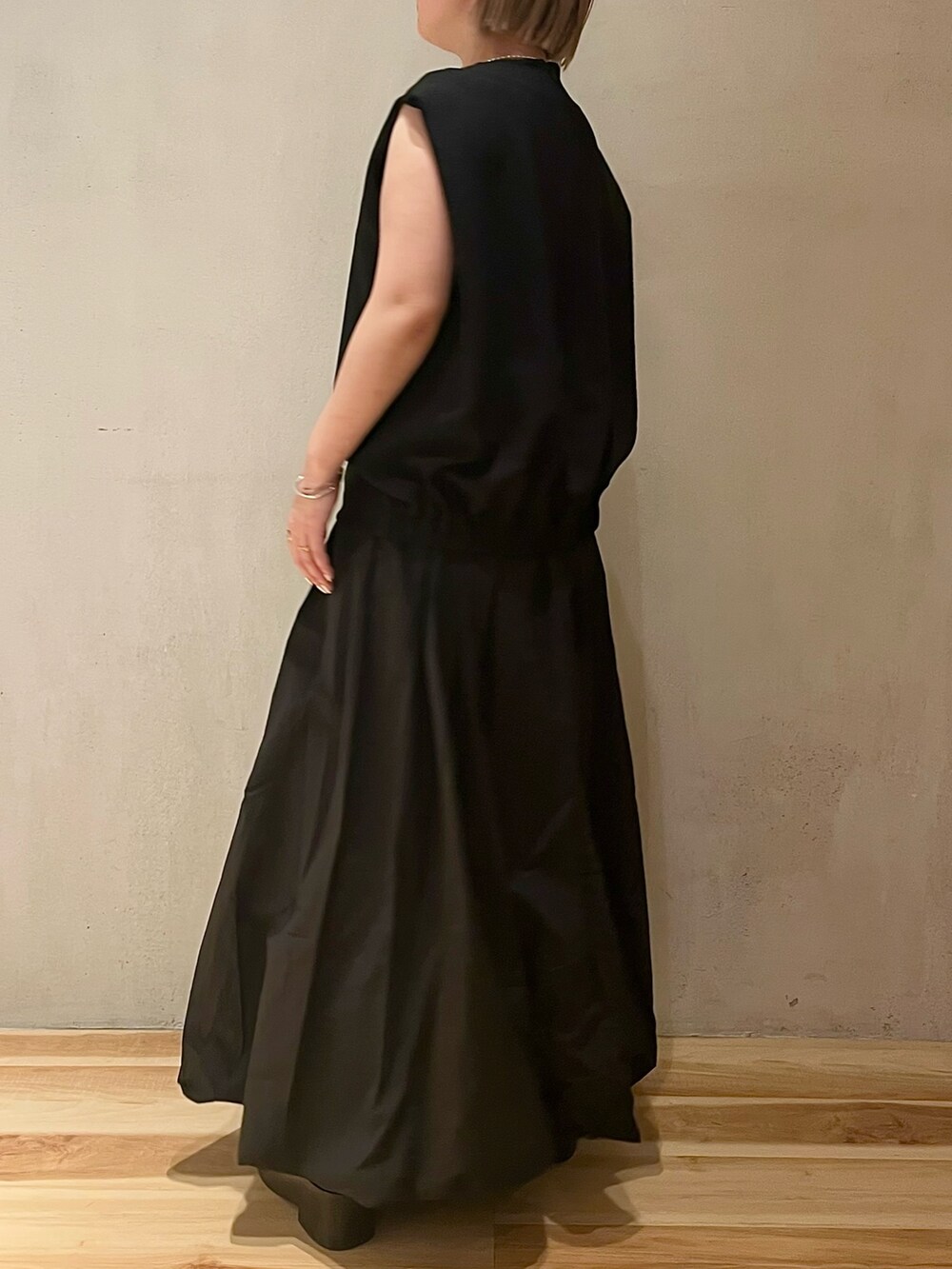 ブラック系のワンピース、ブラック系のブーツを着用したレディースの春コーディネートの2枚目の写真