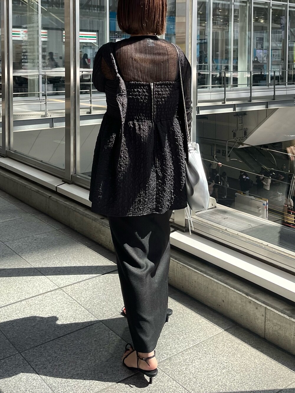 ブラック系のニット/セーター、ブラック系のシャツ/ブラウス、シルバー系のショルダーバッグを着用したレディースの春コーディネートの2枚目の写真