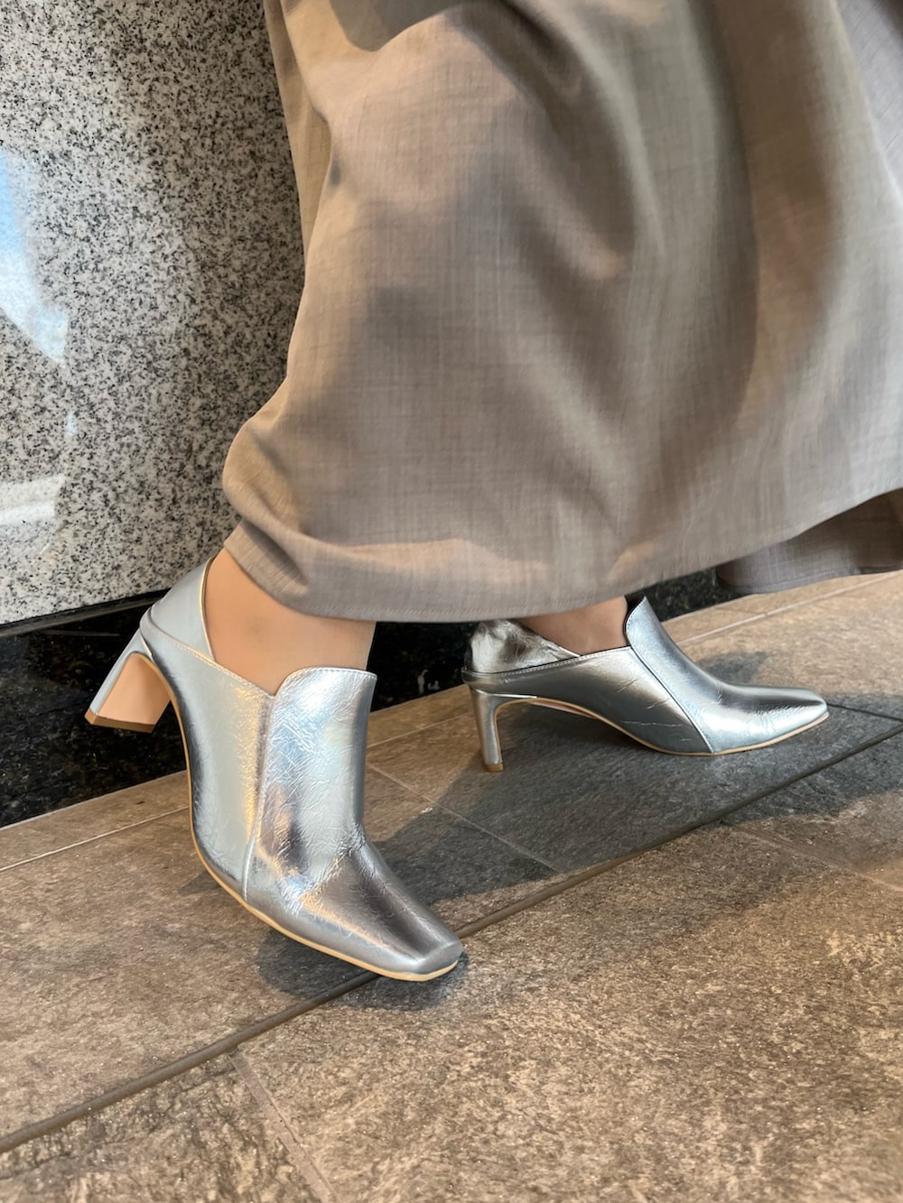 グレー系のワンピース、シルバー系のハンドバッグ、シルバー系のブーツを着用したレディースの夏コーディネートの10枚目の写真