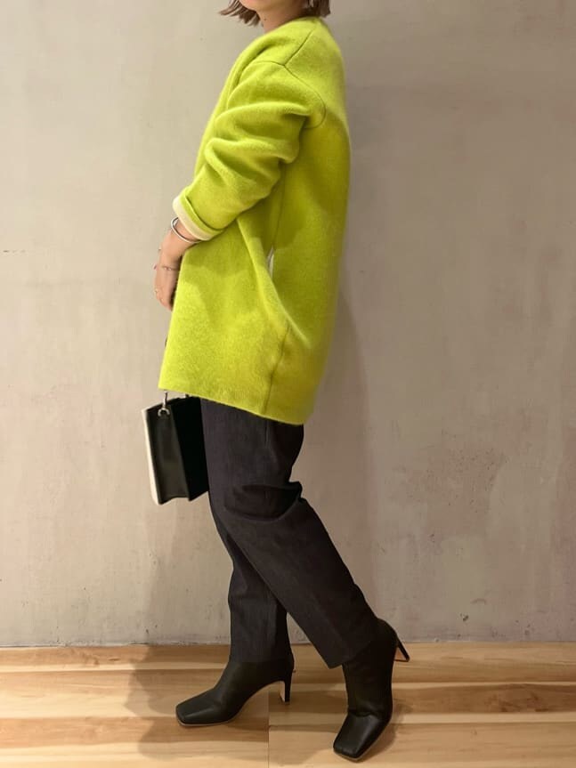 ホワイト系のショルダーバッグ、イエロー系のカーディガン/ボレロ、ブラック系のブーツを着用したレディースの秋コーディネートの2枚目の写真