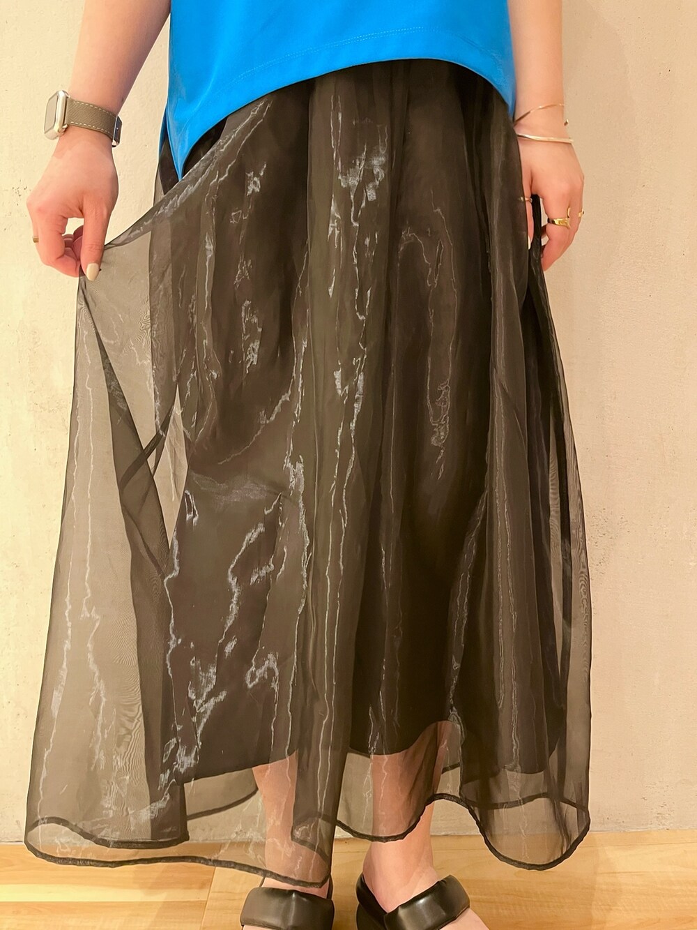 ブルー系のTシャツ/カットソー、ブラック系のスカート、ブラック系のサンダルを着用したレディースの冬コーディネートの8枚目の写真