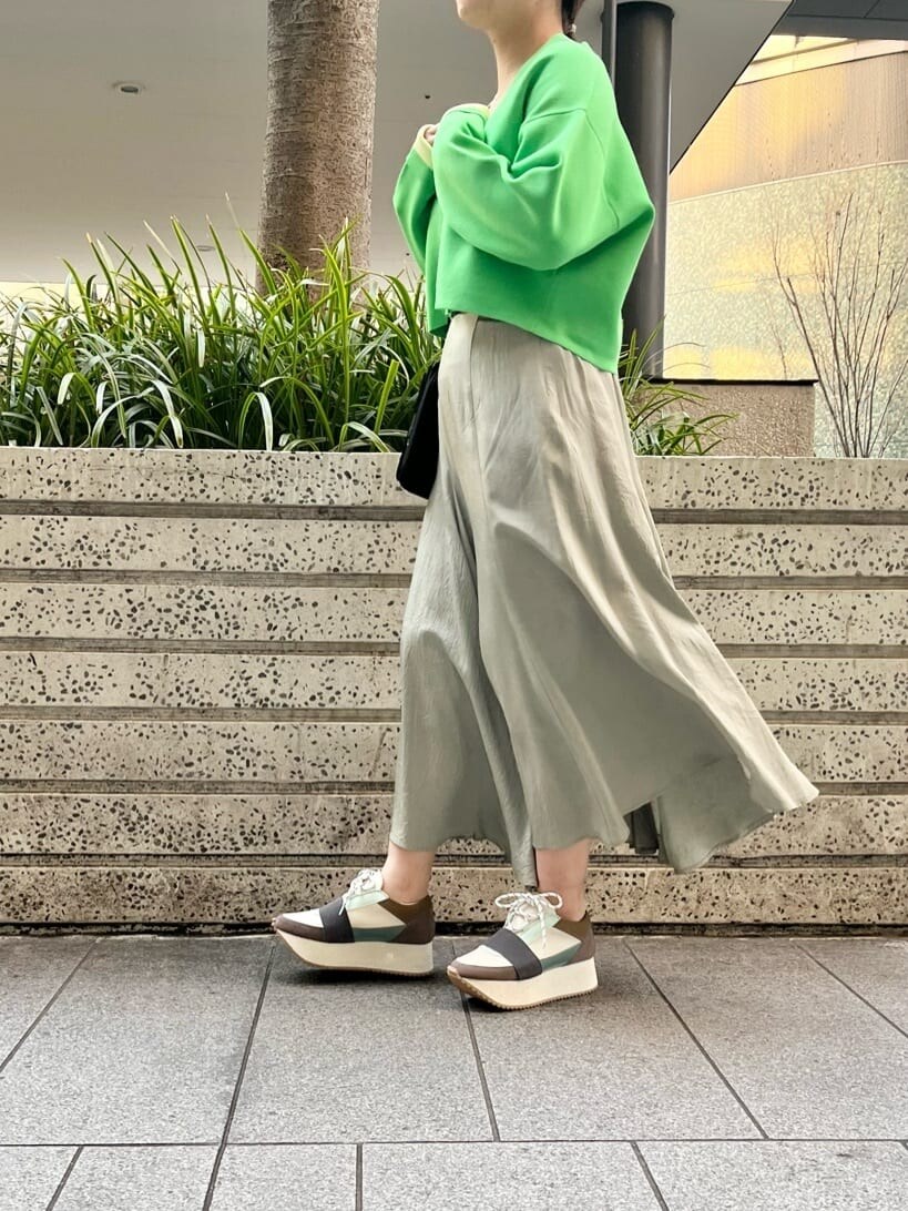 グリーン系のスニーカー、グリーン系のスカート、グリーン系のカーディガン/ボレロを着用したレディースの春コーディネートの2枚目の写真