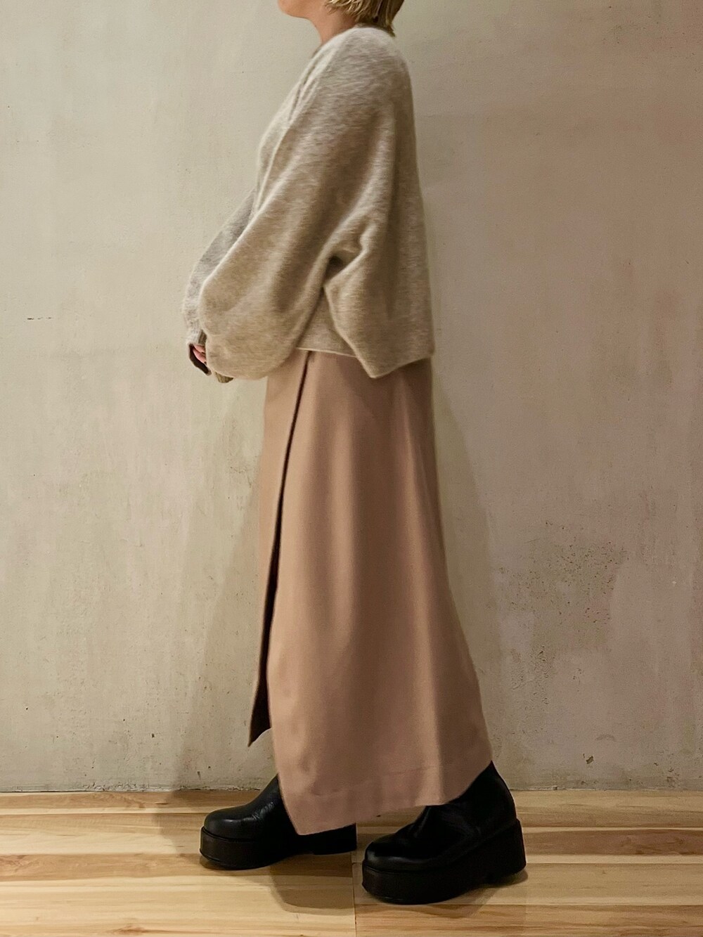 ベージュ系のニット/セーター、ベージュ系のスカート、ブラック系のブーツを着用したレディースの秋コーディネートの3枚目の写真