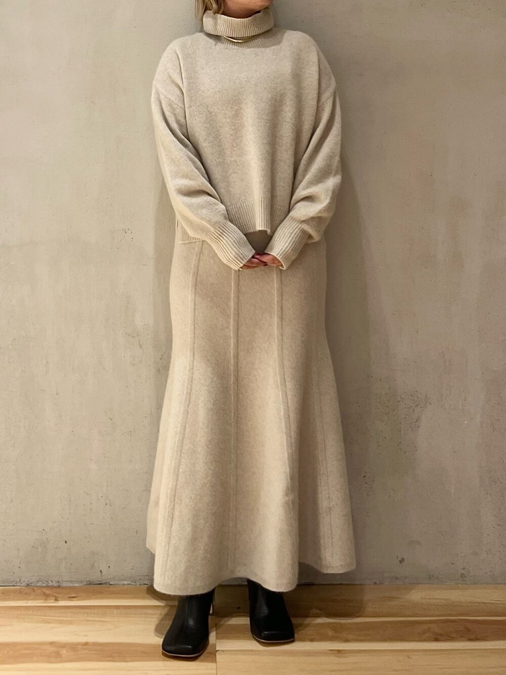 ブラック系のノーカラーコート、ホワイト系のニット/セーター、ホワイト系のスカートを着用したレディースの秋コーディネートの8枚目の写真