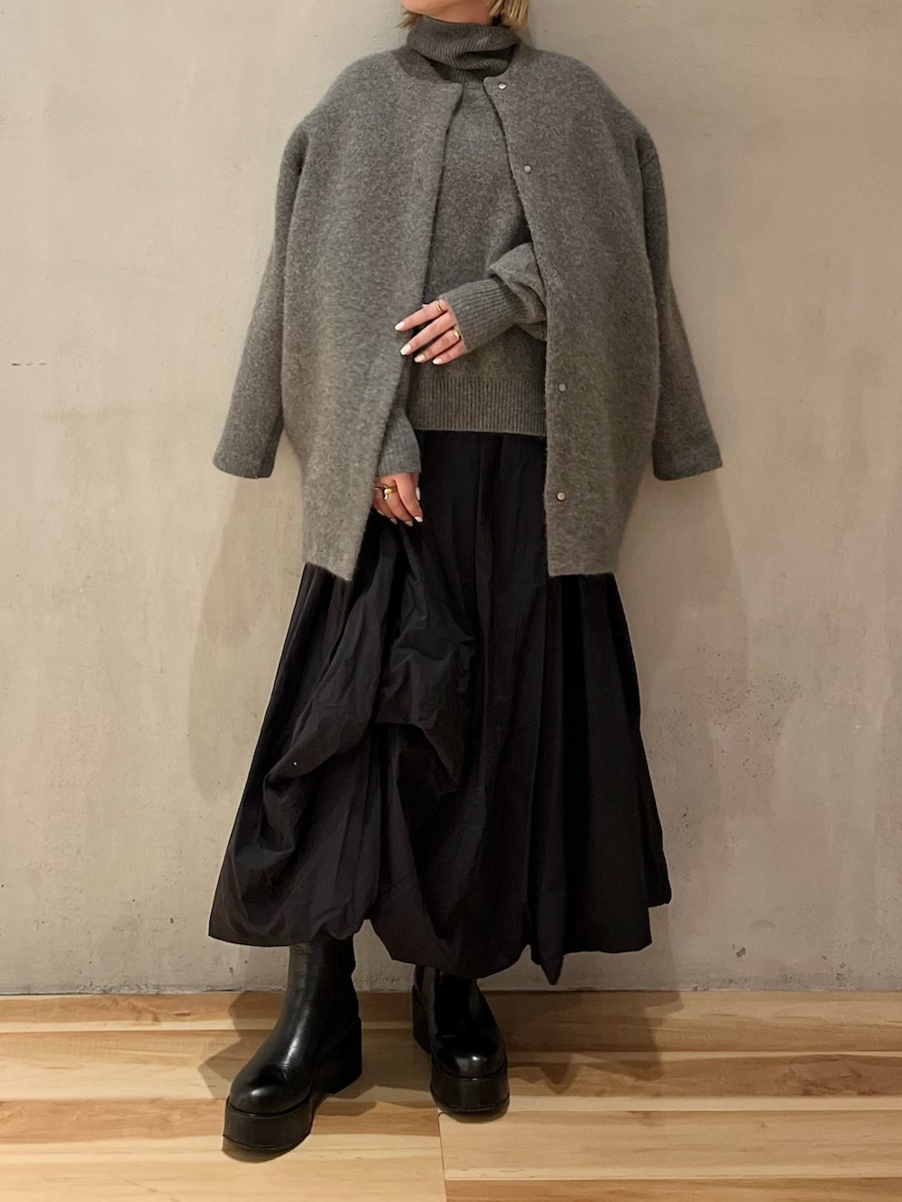 グレー系のニット/セーター、ブラック系のスカート、ブラック系のブーツを着用したレディースの冬コーディネートの4枚目の写真