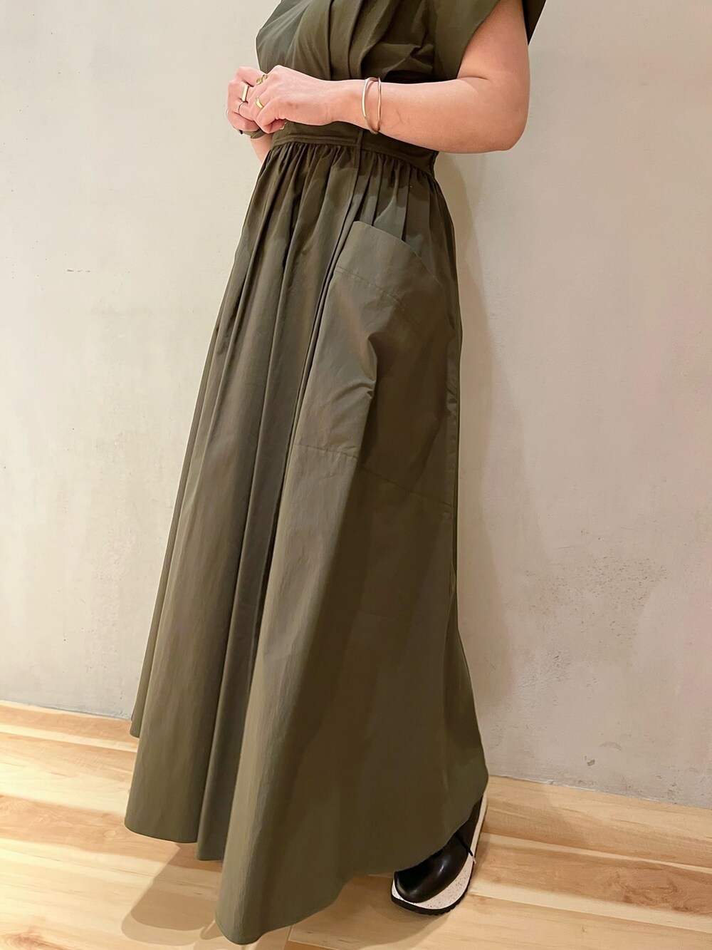 グリーン系のワンピース、ブラック系のスニーカー、シルバー系のネックレスを着用したレディースの冬コーディネートの7枚目の写真