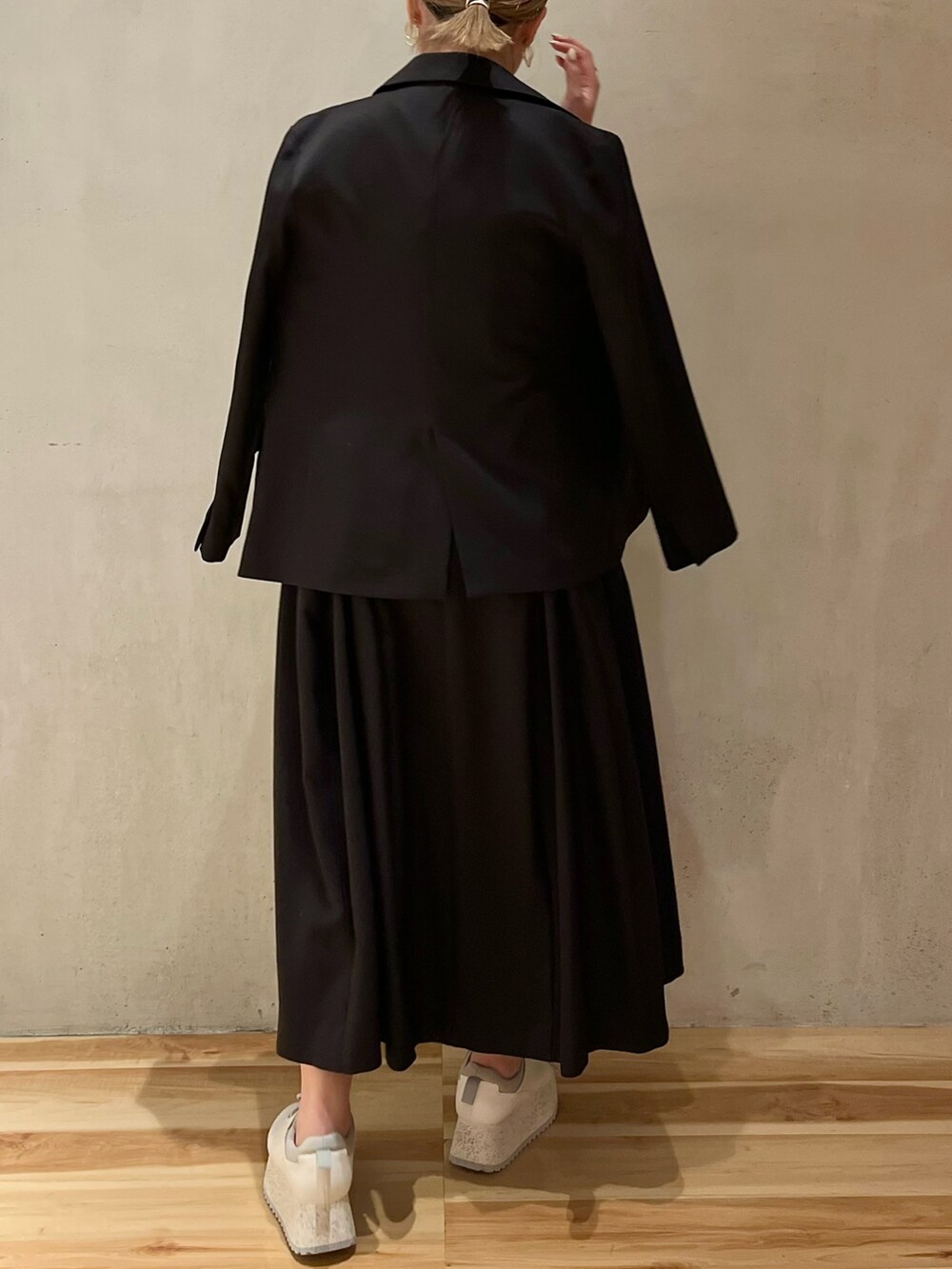 ブラック系のテーラードジャケット、ブラック系のワンピース、ホワイト系のスニーカーを着用したレディースの冬コーディネートの2枚目の写真