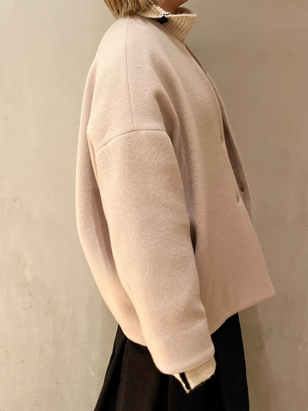 ベージュ系のノーカラーコート、ブラック系のスカート、ブラック系のブーツを着用したレディースの夏コーディネートの6枚目の写真