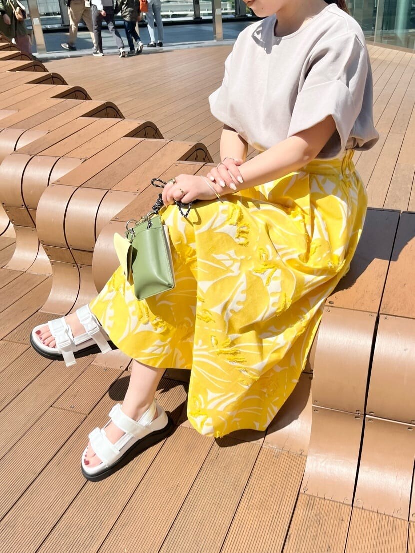 イエロー系のショルダーバッグ、イエロー系のスカート、ホワイト系のサンダルを着用したレディースの春コーディネートの4枚目の写真