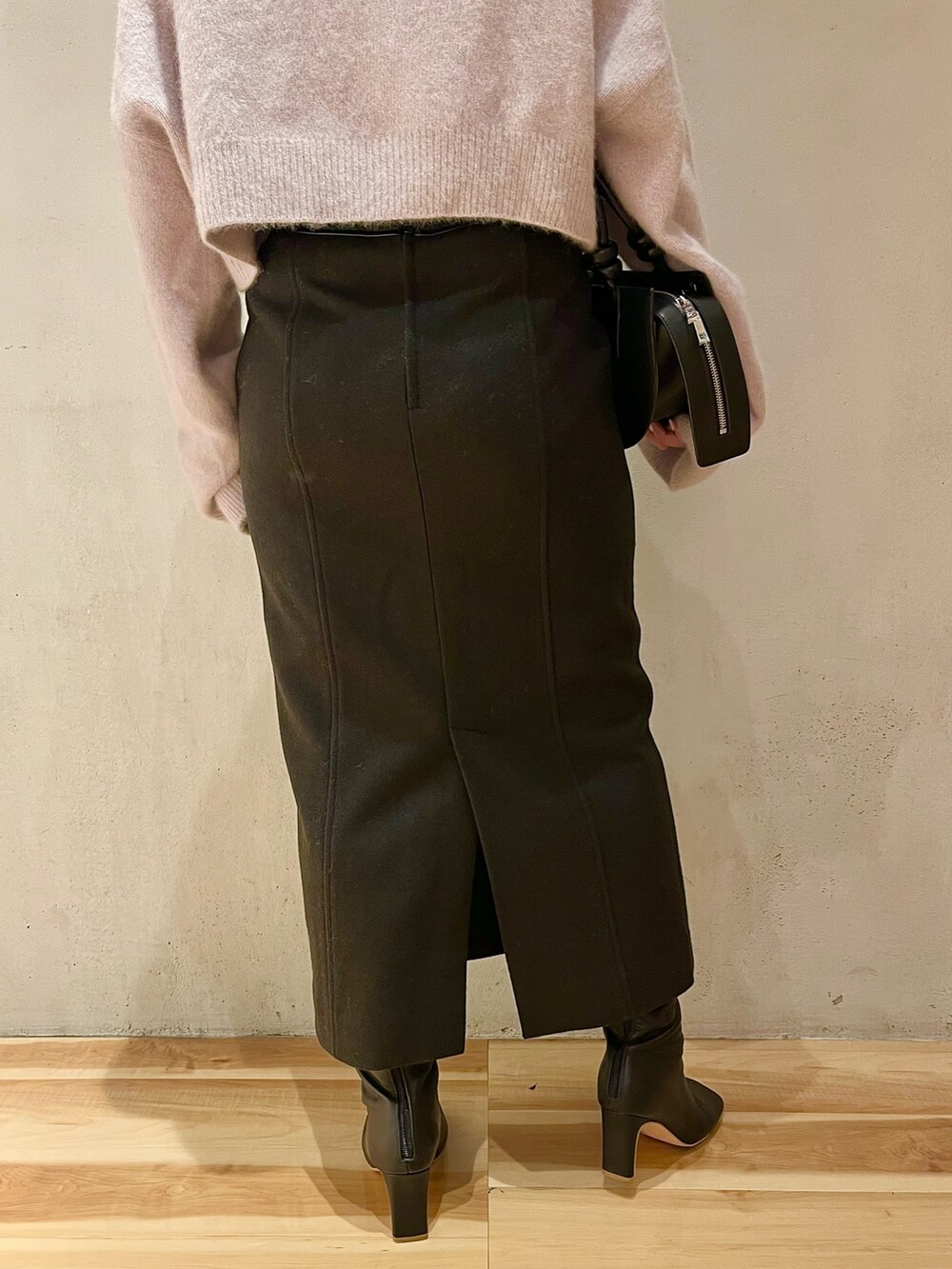 ブラック系のスカート、ブラック系のブーツ、ブラック系のハンドバッグを着用したレディースの秋コーディネートの8枚目の写真